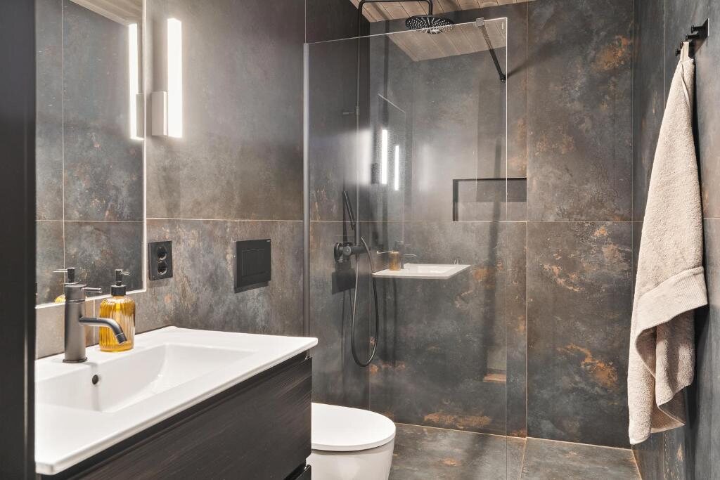 A bathroom in dark stone tiles with a rain shower