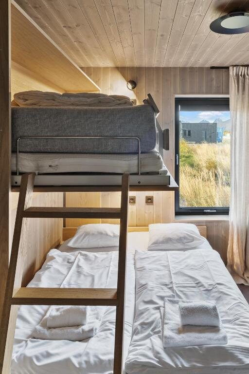 A bedroom with a bunk above a large double bed, and a window onto the heath