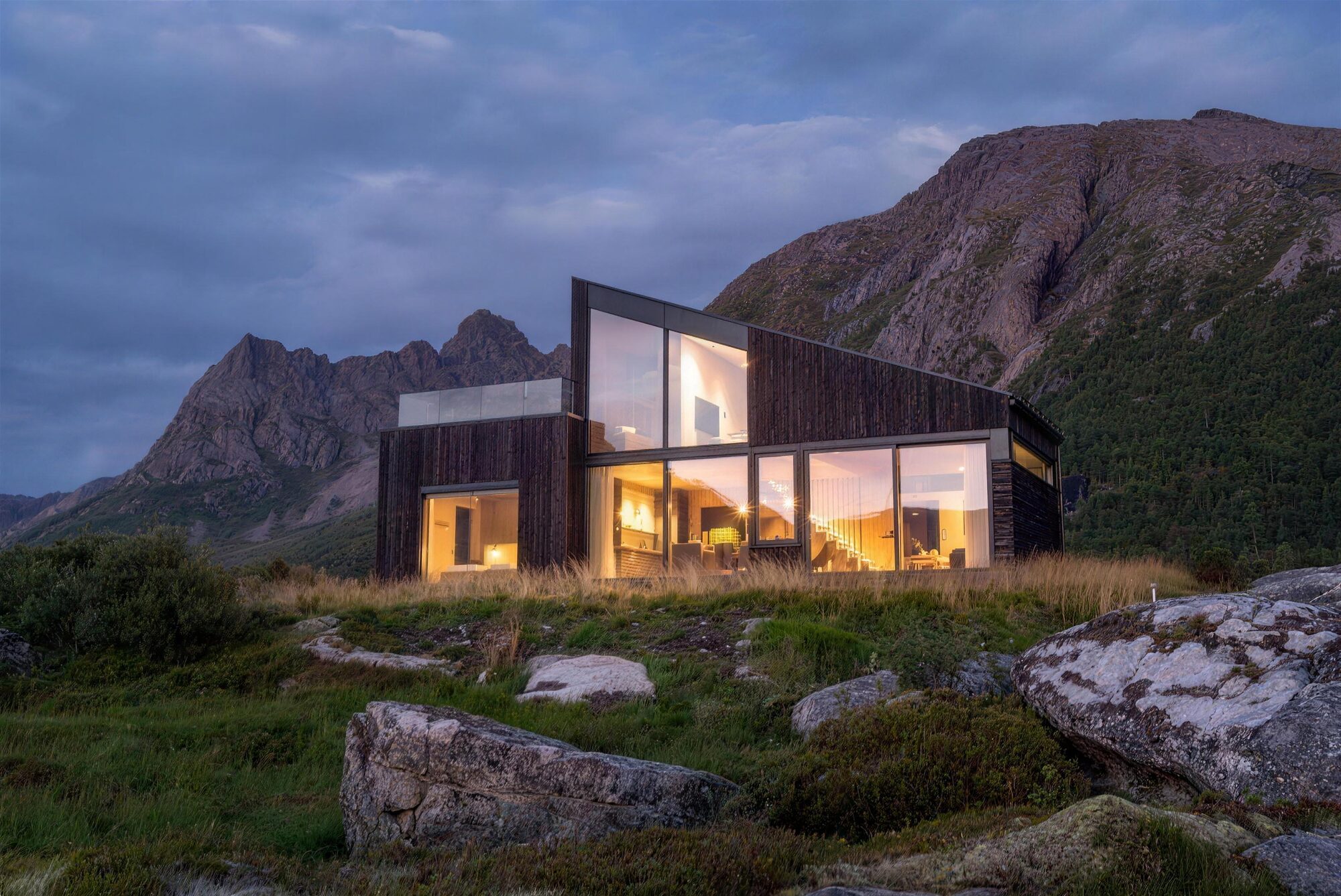 Hoda Cabin lit up at dusk, with the Lofoten mountains behind